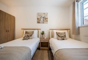 two beds with teddy bears sitting on them in a room at Greenacres in Kelsale