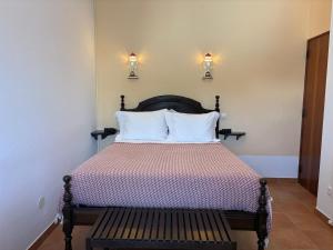 a bedroom with a bed and a bench with lights on the wall at Cabo de Sagres -1 bedroom apartment in Sagres