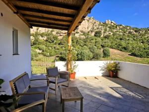 a patio with chairs and a table and a mountain at Lu Lisandru in Abbiadori