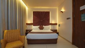 a hotel room with a bed and a chair at Hotel Heritage Grand in Thane