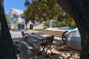 a table and chairs in a yard with a pool at Asteria Eco Finca Sustainable 6 Bedroom Nature Retreat near UNVRS Ibiza in Santa Gertrudis de Fruitera