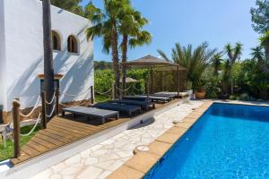 a swimming pool with benches next to a villa at Asteria Eco Finca Sustainable 6 Bedroom Nature Retreat near UNVRS Ibiza in Santa Gertrudis de Fruitera