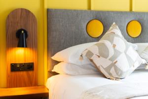 a bed with white pillows and a gray headboard at Base Dingle in Dingle