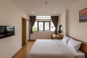 a bedroom with a white bed and a television at Bluzen Hotel in Danang