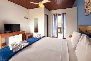 a bedroom with a large white bed with a flat screen tv at Pousada Fruto do Mar in Ilhabela