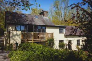 a white house with a porch and a deck at Plasbach Cottage in Llandeilo