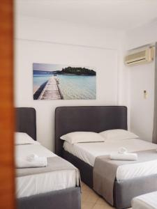 two beds in a room with a picture on the wall at Corner Hotel in Ksamil