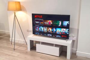 a flat screen tv sitting on top of a white table at Daisy Lodge - Spacious Two Bed Flat - Parking, Netflix, WIFI - Close to Blenheim Palace & Oxford - F1 in Oxford