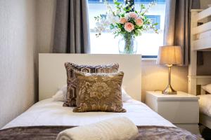 a bedroom with a bed with a pillow and a vase of flowers at Daisy Lodge - Spacious Two Bed Flat - Parking, Netflix, WIFI - Close to Blenheim Palace & Oxford - F1 in Oxford