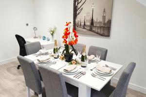 a white dining room table with chairs and flowers on it at Daisy Lodge - Spacious Two Bed Flat - Parking, Netflix, WIFI - Close to Blenheim Palace & Oxford - F1 in Oxford