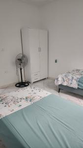 a bedroom with a bed and a fan and a bed at Location saisonnière entre mer, forêt et calme in Raʼs al Jabal