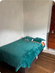 a bed with a green comforter in a room at Tarmeñita VIP in Tarma