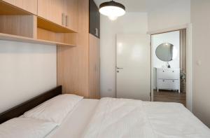 a bedroom with a white bed and a mirror at Aurea Tivat Apartment in Tivat