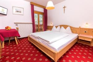 a bedroom with a bed and a red carpet at Garni Rives in Ortisei