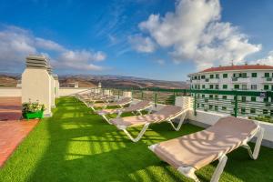 a row of lounge chairs on the roof of a building at RT-Green Park in Playa del Ingles