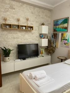 a living room with a flat screen tv on a brick wall at Unejs Apartment in Berat