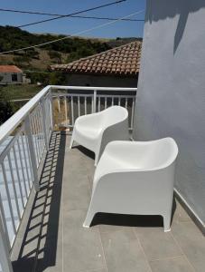 two white chairs sitting on a balcony at Romanou Guest House in Romanón +3 photos