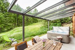a patio with a hot tub and a table and chairs at Chalet Hinter dem Rot Stei, private wellness, in ski and hiking area of Zermatt in Zermatt