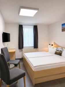 a bedroom with a large bed and a chair at Hotel Pension Vineta Rügen in Baabe