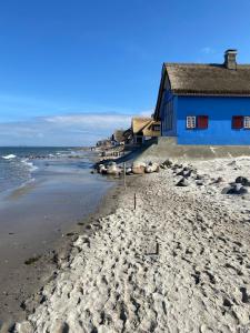 a blue building on a sandy beach next to the ocean at Haus Dani in Oldenburg in Holstein