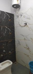 a bathroom with a toilet and a marble wall at Om Dayama Please in Khātu