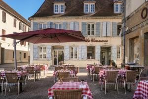 a group of tables and chairs with an umbrella in front of a building at Hôtel Restaurant Le Commerce in Navarrenx