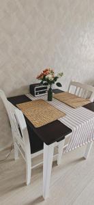 a white table with two chairs and a vase with flowers at Sorvarinraitin sydän in Seinäjoki