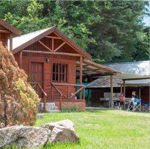 a log cabin with people sitting at a table outside at Complejo Bellotas in Agua de Oro