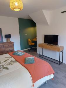 a bedroom with a bed with a television and a desk at La Maison d'André in Digny