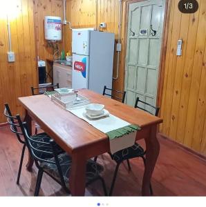 a wooden table with chairs and a refrigerator in a kitchen at Complejo Bellotas in Agua de Oro +5 photos