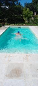 a man swimming in a swimming pool at Complejo Bellotas in Agua de Oro