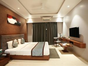 a bedroom with a bed and a desk and a television at Alaukik Hotel in Shirdi