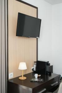 a room with a desk with a television on a wall at Hôtel Restaurant Le Commerce in Navarrenx
