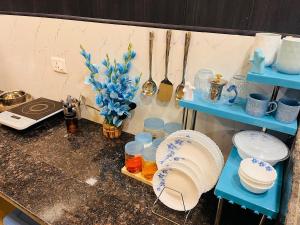 a kitchen counter with blue shelves and plates and utensils at Ophelia in Agra +16 photos