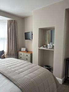 a bedroom with a bed and a television in it at Canterbury Guest House in Sidmouth