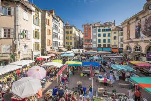 a crowd of people walking around a market with umbrellas at Appartement Grenouillit, hyper centre du Puy in Le Puy-en-Velay