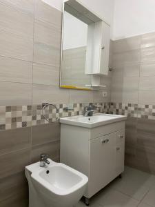 a white bathroom with a sink and a mirror at Unejs Apartment in Berat +31 photos