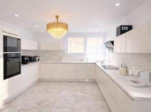 a kitchen with white cabinets and a chandelier at Maison exceptionnelle - 6 pers - 3 chambres - Centre in Sablé-sur-Sarthe +14 photos