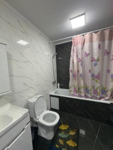 a bathroom with a toilet and a sink and a shower curtain at Omurbek Guesthouse in Sary-Mogul +34 photos