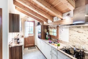 a kitchen with white cabinets and wooden ceilings at Chalet Hinter dem Rot Stei, private wellness, in ski and hiking area of Zermatt in Zermatt +39 photos