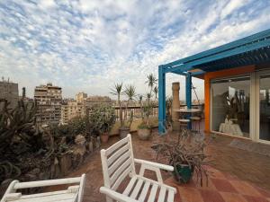 two white chairs on a patio with a view of a city at Zenith Cairo Deluxe Room Shared Apartment in Cairo