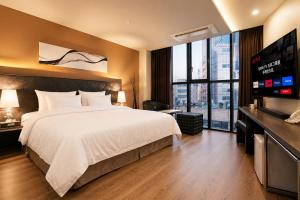 a hotel room with a bed and a flat screen tv at Seoul Ahava Hotel in Seoul