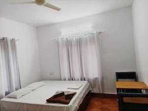 a white bedroom with a bed with white curtains at H Villa in Nilambūr