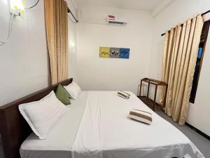 a small room with a bed with two shoes on it at Lumieri Hotel Arugambay in Arugam Bay +2 photos