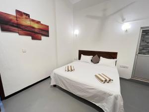 a bedroom with a white bed with two chairs on it at Lumieri Hotel Arugambay in Arugam Bay