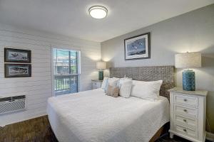 a bedroom with a bed with white sheets and a window at Bay Tree A3 in Port Aransas