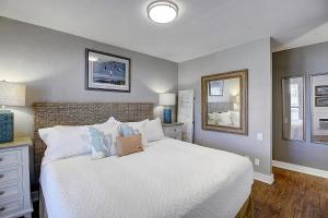 a bedroom with a white bed and a mirror at Bay Tree A3 in Port Aransas