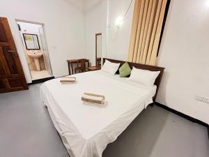 a bedroom with a bed with white sheets and a mirror at Lumieri Hotel Arugambay in Arugam Bay