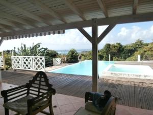 ein Holzdeck mit einer Bank neben einem Swimmingpool in der Unterkunft Villa Alizea in Capesterre