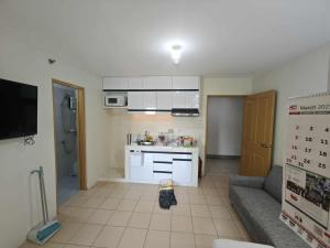 a kitchen with white cabinets and a couch in a room at Steve's Condo in Davao City